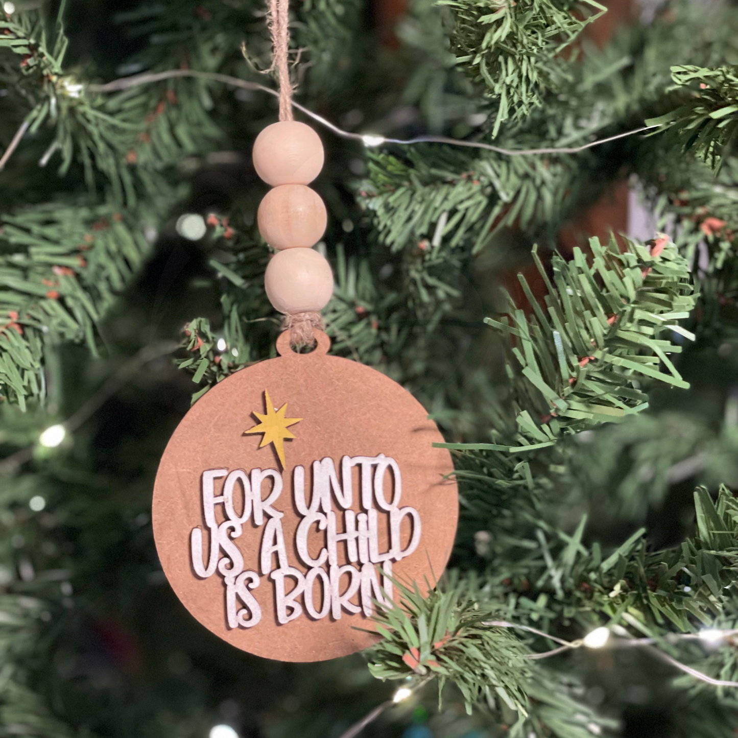 Handcrafted wooden Christmas ornament with "For Unto Us A Child Is Born" on a tree.