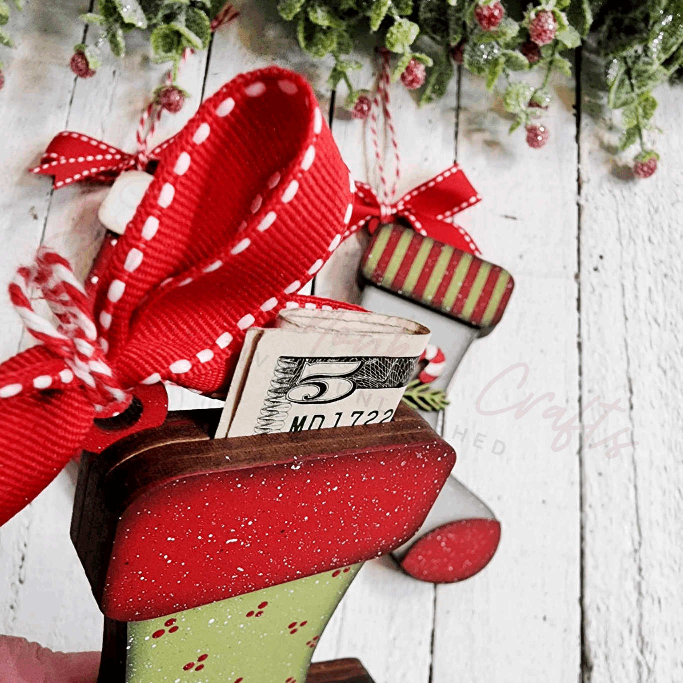 Paintable stocking ornament with red ribbon and money holder on a wooden surface, part of a crafting set.