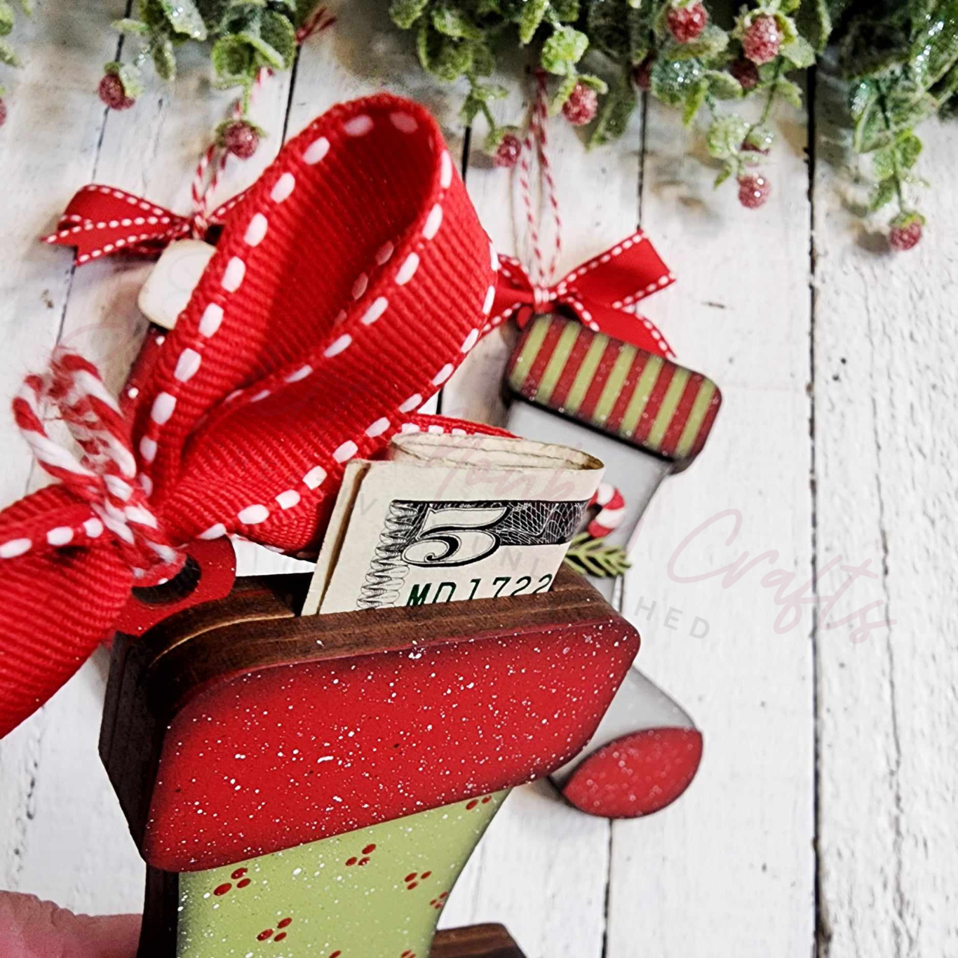 Paintable stocking ornament with red ribbon and money holder on a wooden surface, part of a crafting set.