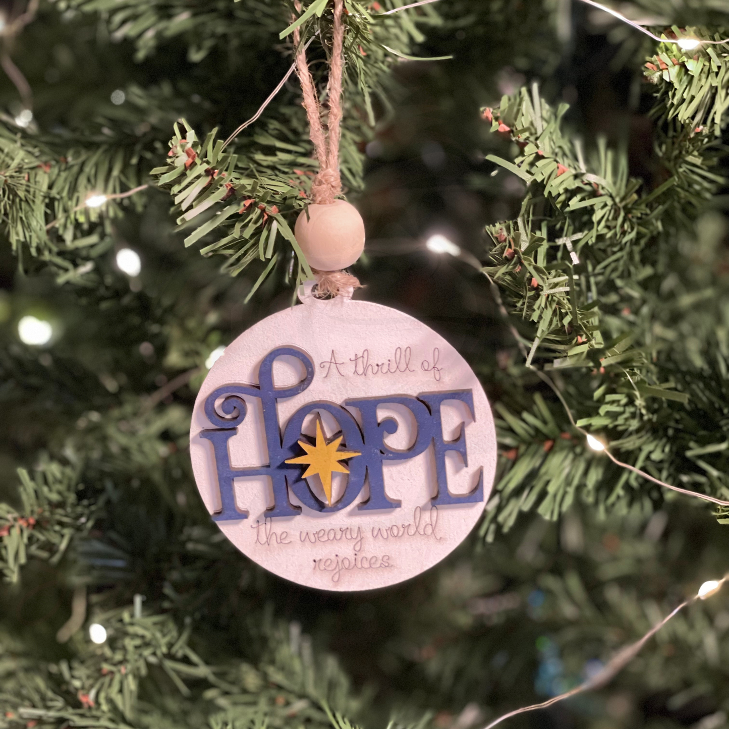 Handcrafted round Christmas ornament with "Hope" design on a tree.