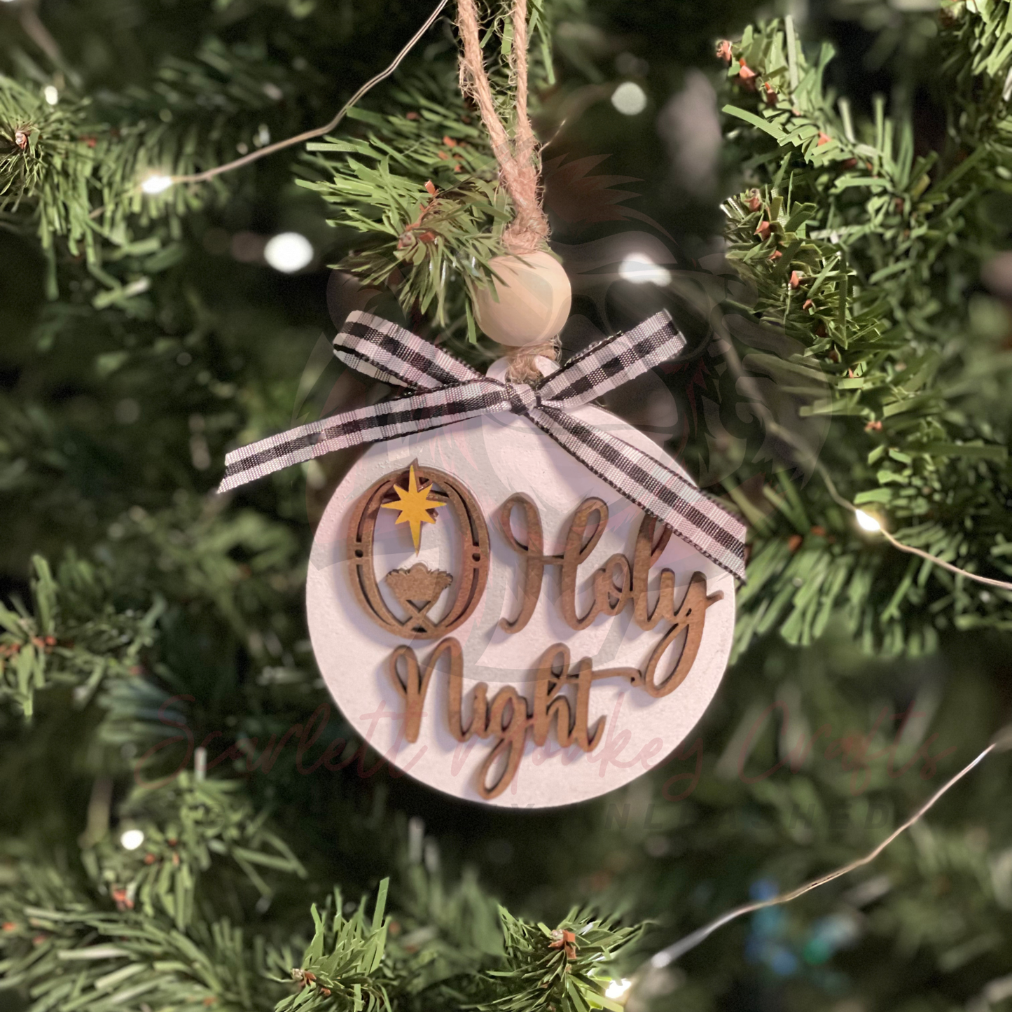 Hand-painted wooden Christmas ornament with O Holy Night lettering and manger detail hanging on tree with twine and bead