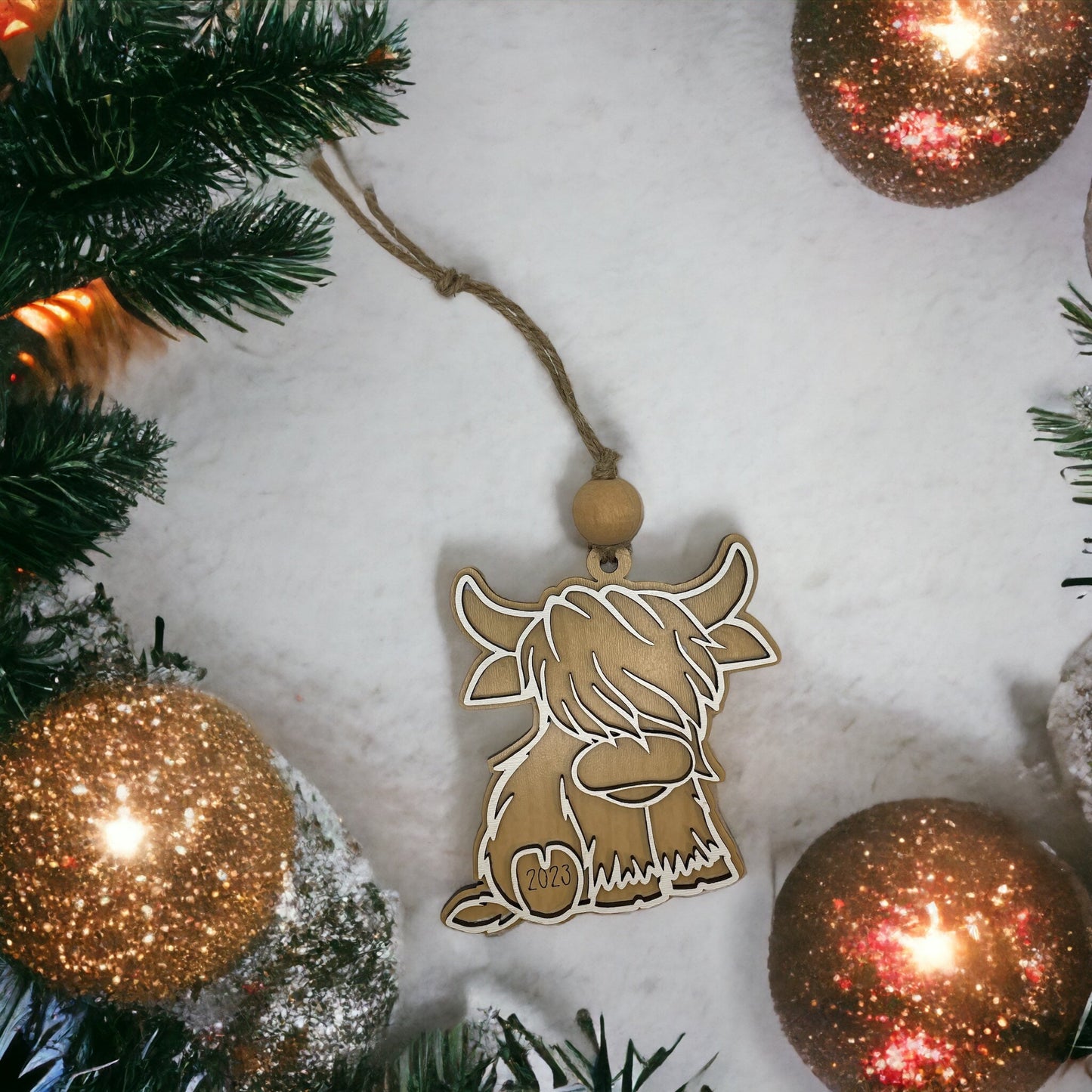 Christmas ornament featuring a Highland cow design among festive decorations.