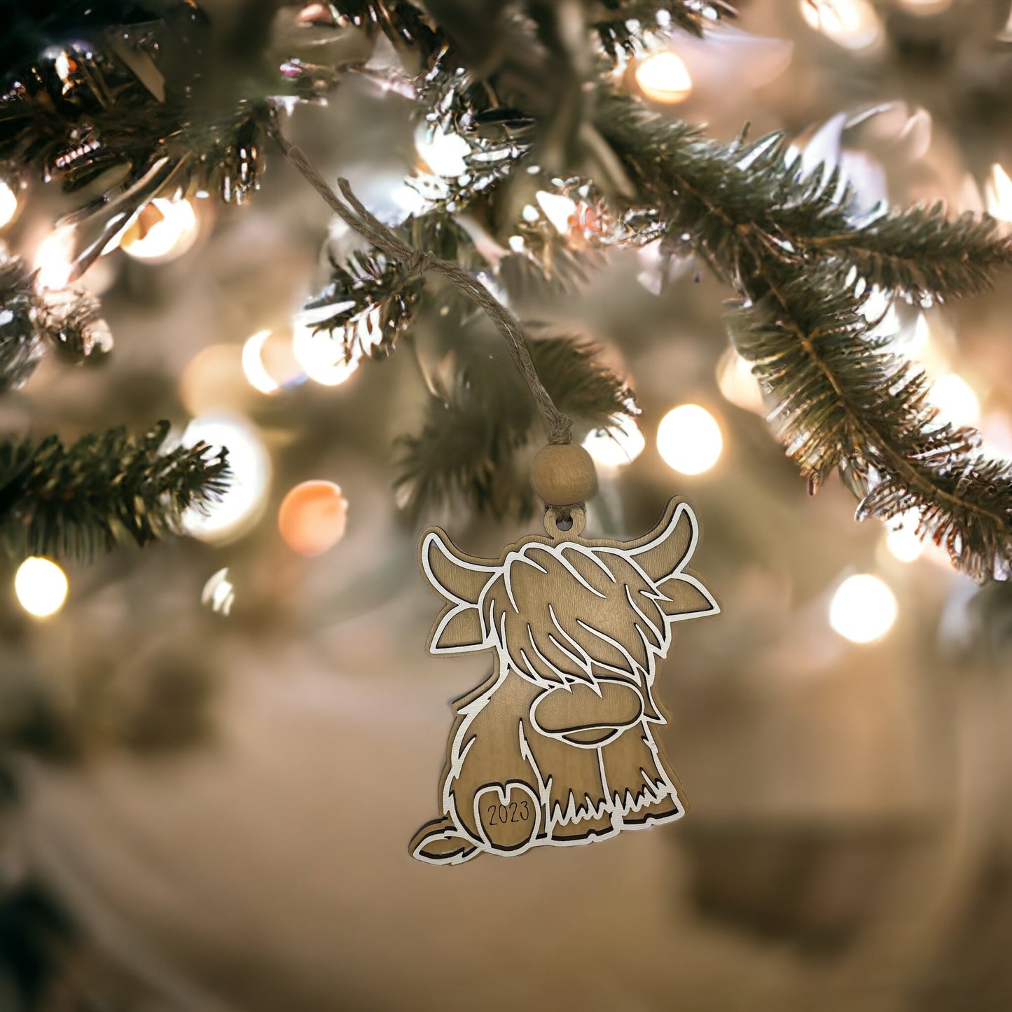 Christmas ornament featuring a Highland cow hanging on a tree.