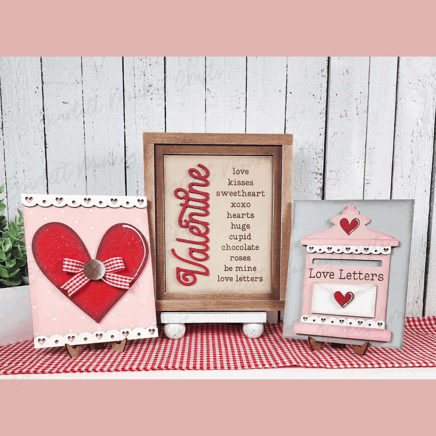 Valentine's Day paintable wood trio signs with heart and love themes displayed on easels.