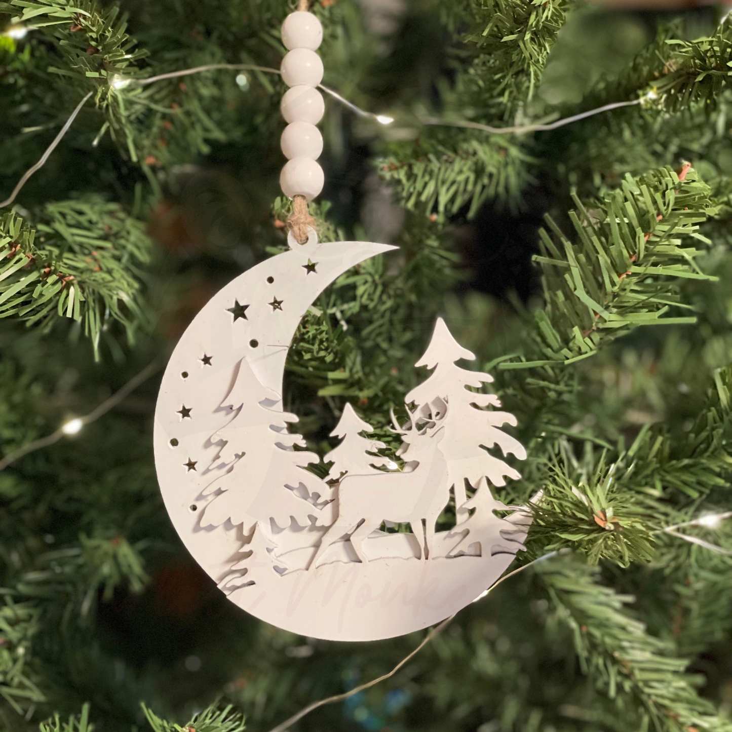 Moon Woodland Christmas Ornament with deer and trees hanging on a Christmas tree.