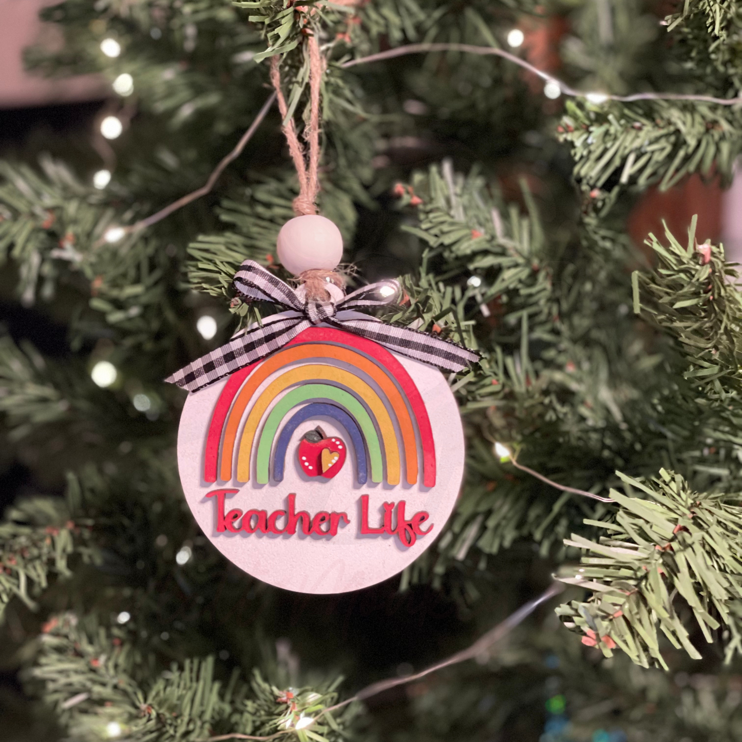 Handcrafted wooden Christmas ornament with "Teacher Life" design hanging on a tree.