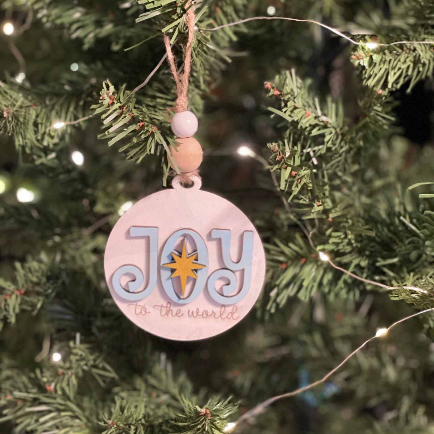 Handcrafted Christmas Ornament - Joy hanging on tree, featuring "Joy to the world" design, 3.43 inches round.