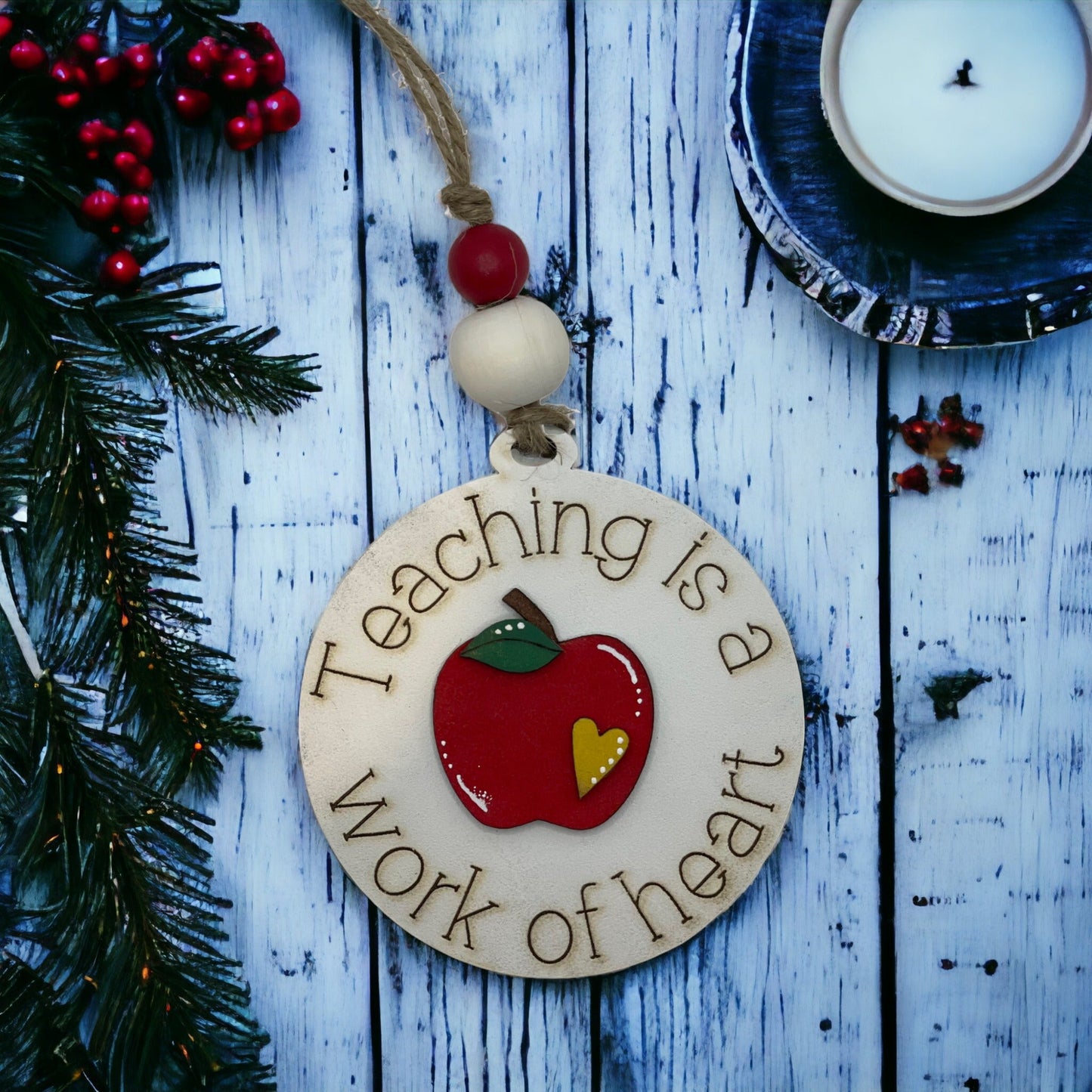 Handcrafted round Christmas ornament with "Teaching Is a Work of Heart" design, featuring vibrant colors and apple motif, perfect gift for teachers.