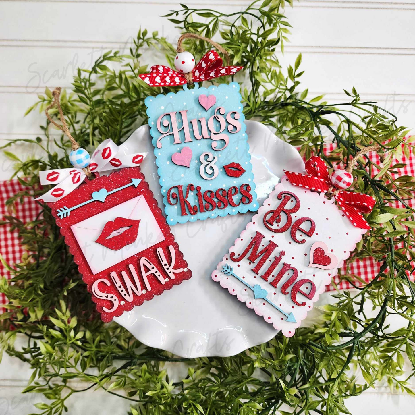 Paintable wood Valentine gift card tags set on a white plate, featuring "Hugs & Kisses" and "Be Mine" designs.
