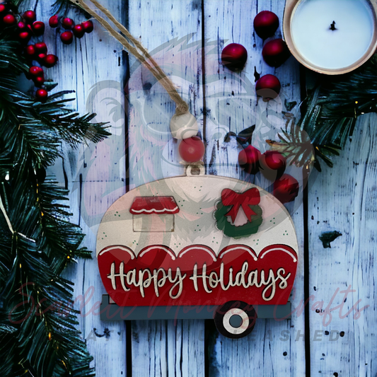 Hand-painted wooden Christmas ornament featuring a red Happy Holidays camper design with wreath and hanging string.