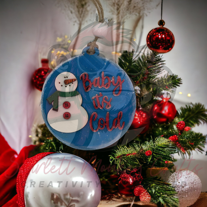 Hand-painted "Baby It's Cold" wooden Christmas ornament with snowman design hanging on festive tree