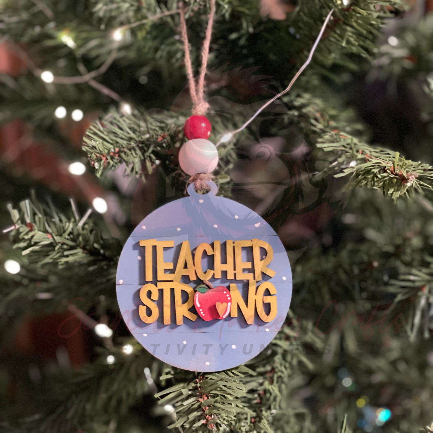 Hand-painted wooden Christmas ornament with Teacher Strong lettering and festive accents hanging on tree