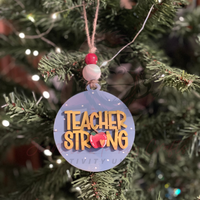Hand-painted wooden Christmas ornament with Teacher Strong lettering and festive accents hanging on tree