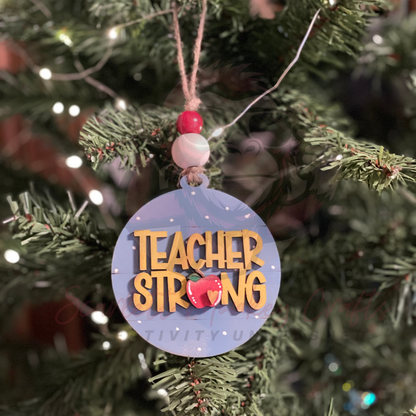 Hand-painted wooden Christmas ornament with Teacher Strong lettering and festive accents hanging on tree