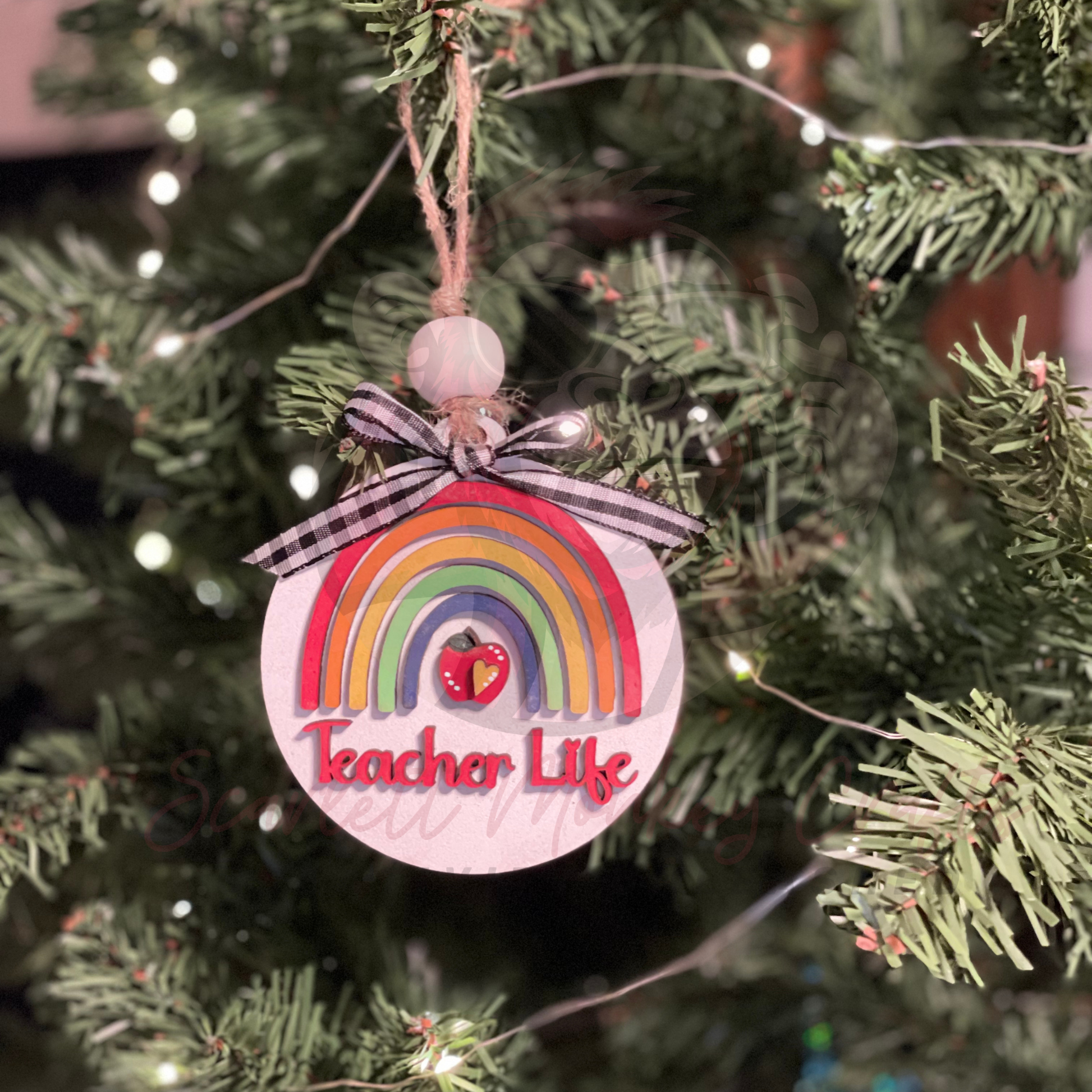 Hand-painted wooden Christmas ornament with rainbow, apple, and Teacher Life lettering hanging on tree