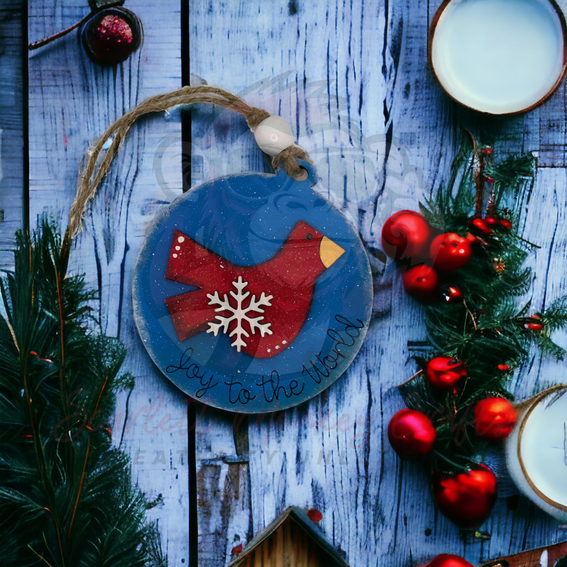Hand-painted wooden Christmas ornament featuring a red cardinal with "Joy to the World" text and natural twine hanger