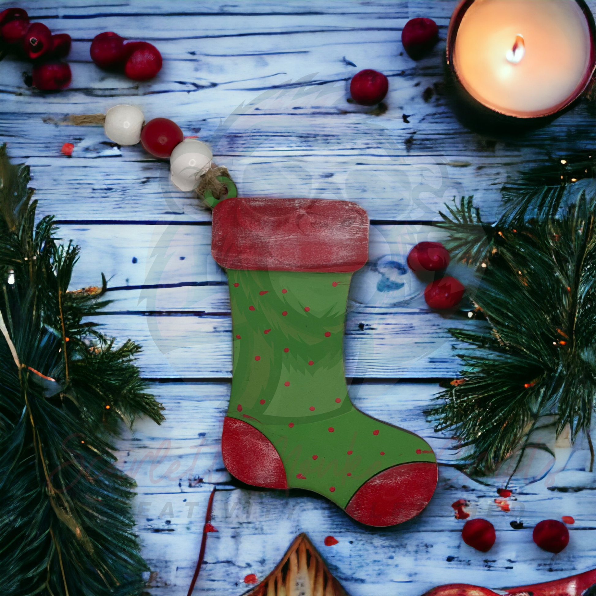 Green painted Christmas stocking ornament money and gift card holder on festive wooden background with candle and pine branches